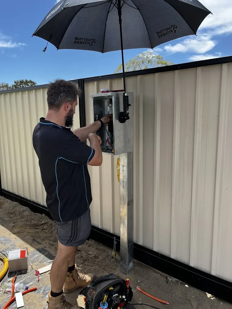 Electrician working on an outdoor electrical switchboard mounted to a consumer pole